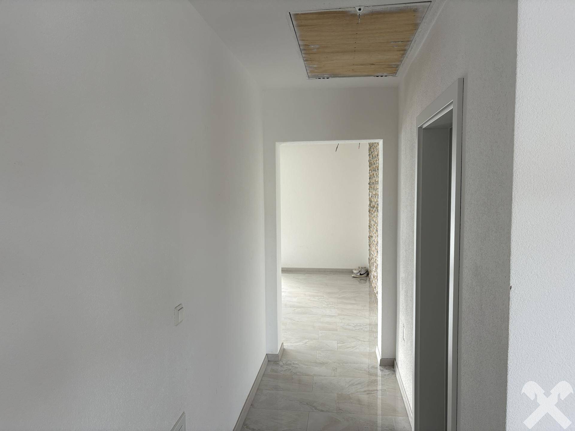 Heller Flur mit Fliesenboden und Zugang zu weiteren Räumen im Haus.