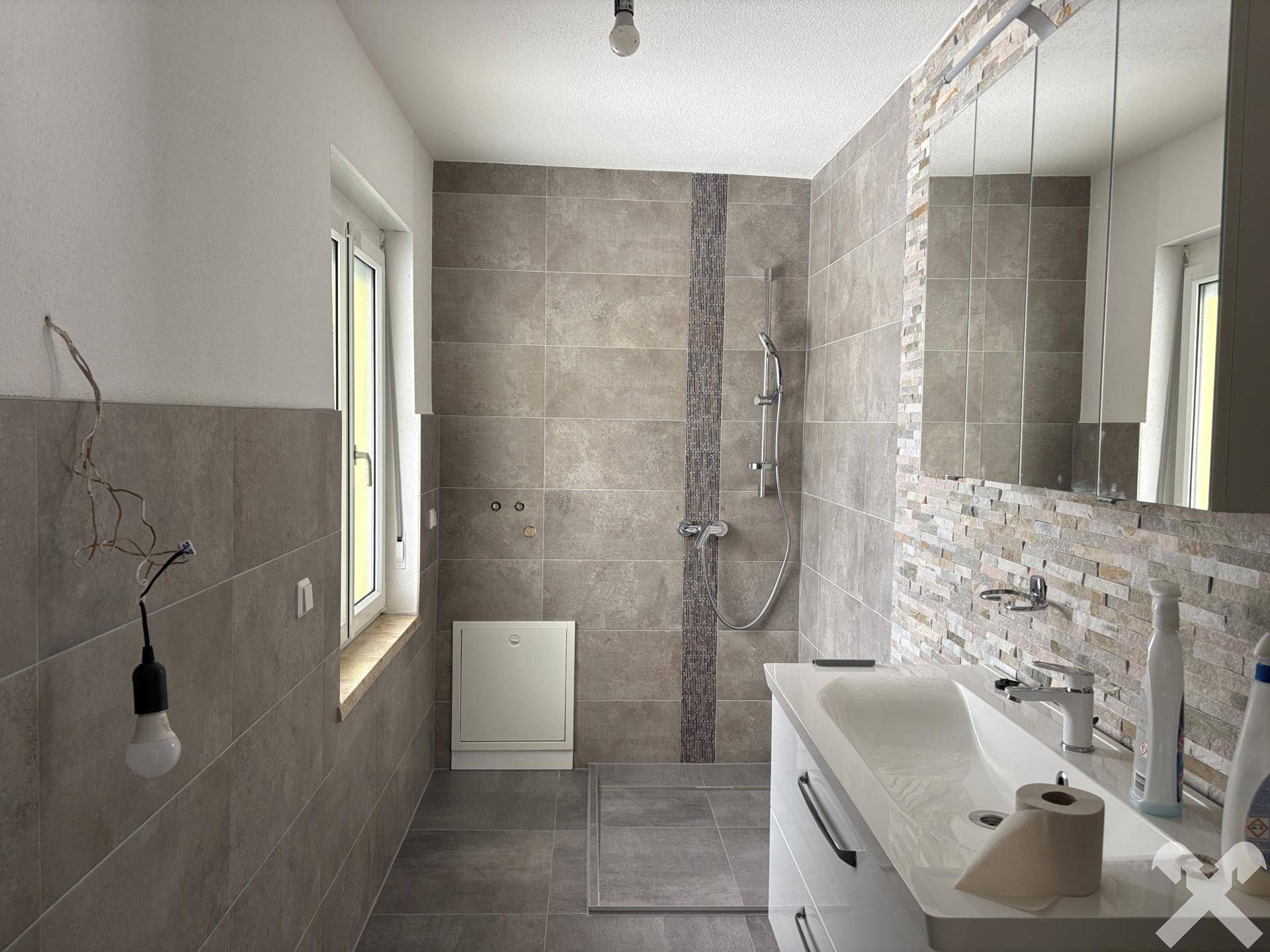 Geräumiges Badezimmer mit begehbarer Dusche, modernen Fliesen und Fenster.