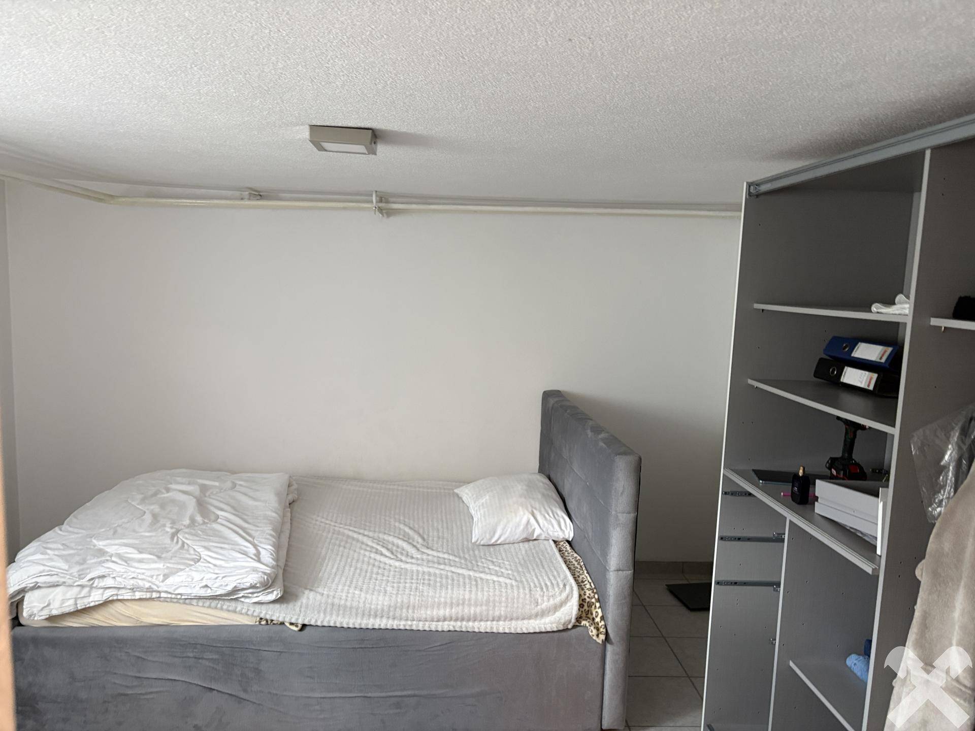 Schlafzimmer im Untergeschoss mit Bett und offenem Kleiderschrank.