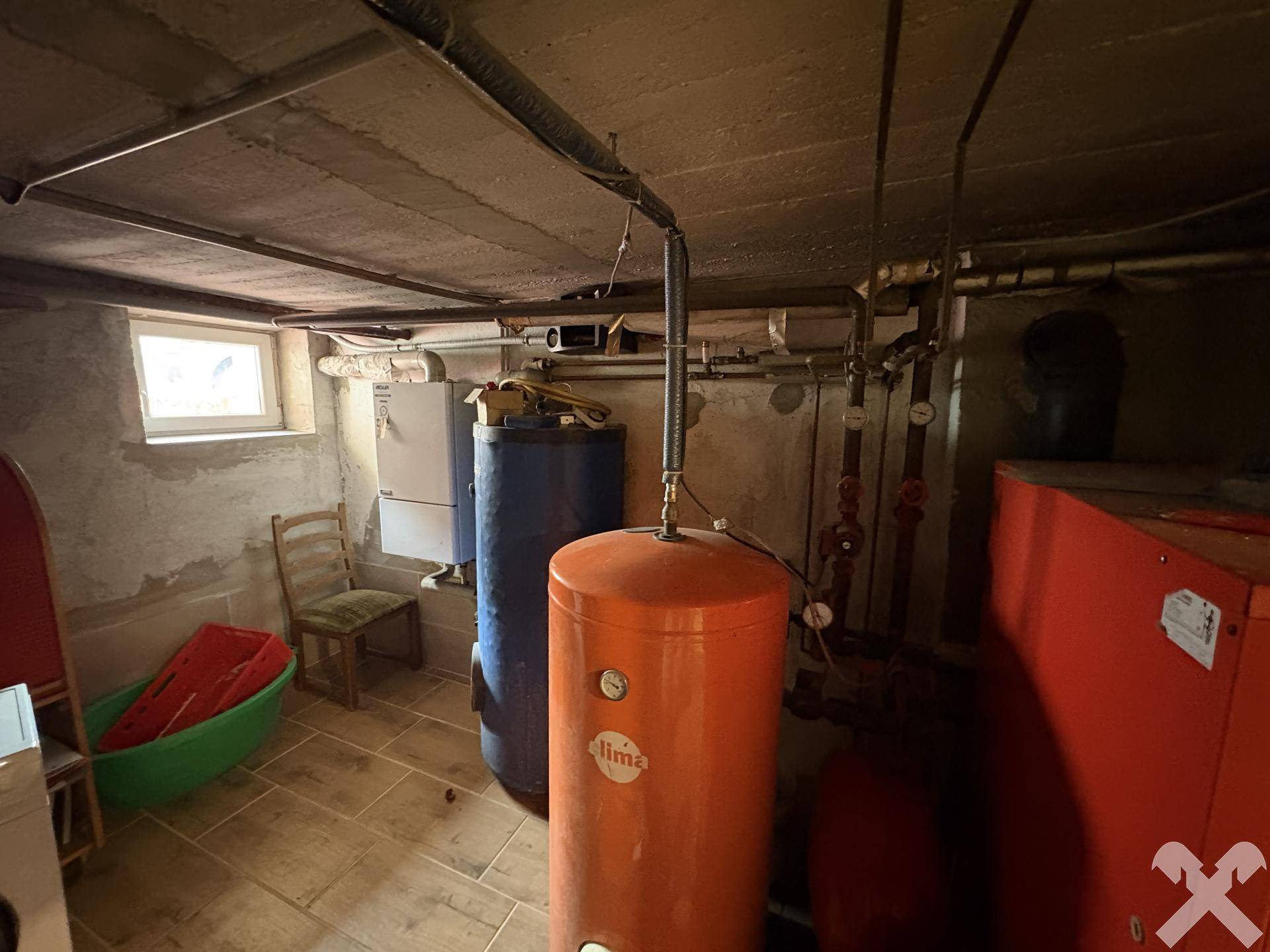 Heizungsraum mit Heizkessel, Warmwasserspeicher und Fenster.
