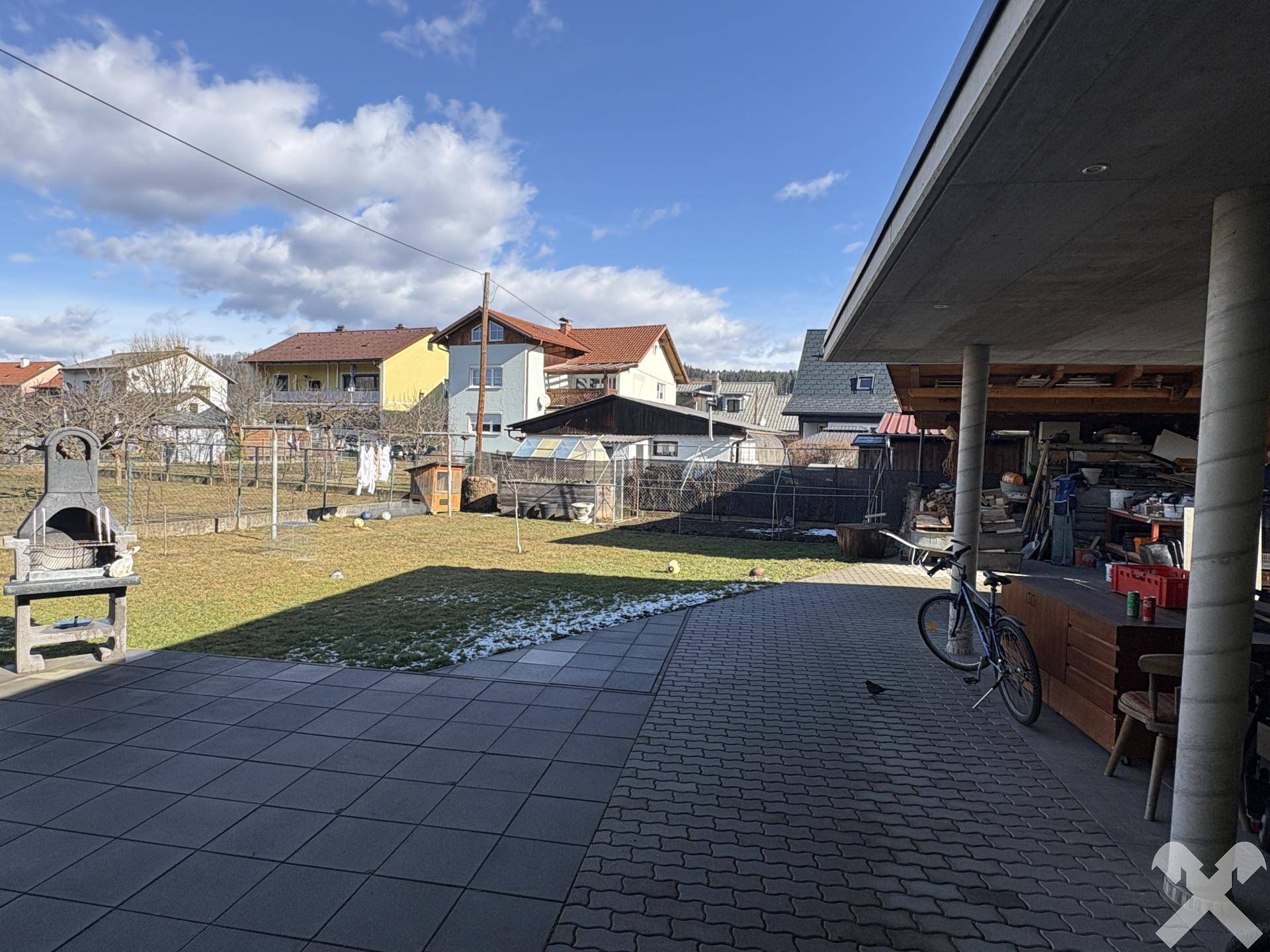 Großer Gartenbereich mit Grillplatz und Blick auf die umliegenden Häuser.