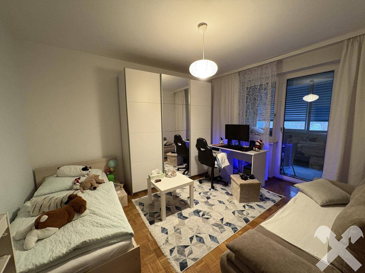 Kinderzimmer oder Arbeitszimmer mit Bett, Schreibtisch und Balkonzugang.