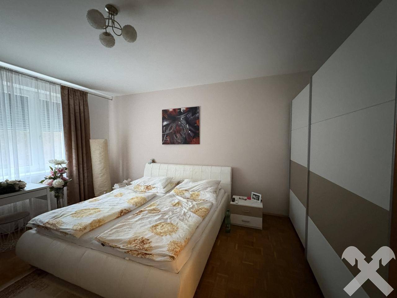 Helles Schlafzimmer mit Einbauschränken, Doppelbett und Parkettboden.