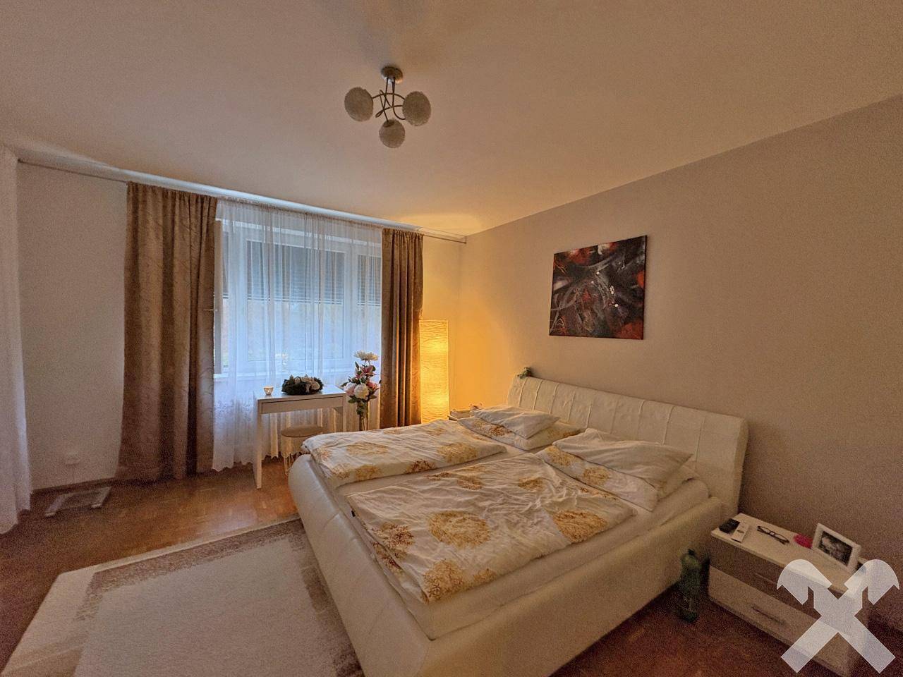 Geräumiges Schlafzimmer mit Doppelbett, Parkettboden und großem Fenster.