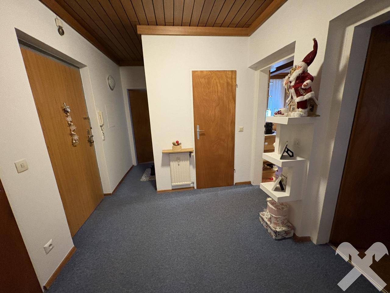 Eingangsbereich mit Teppichboden, Holztüren und dekorativen Elementen.