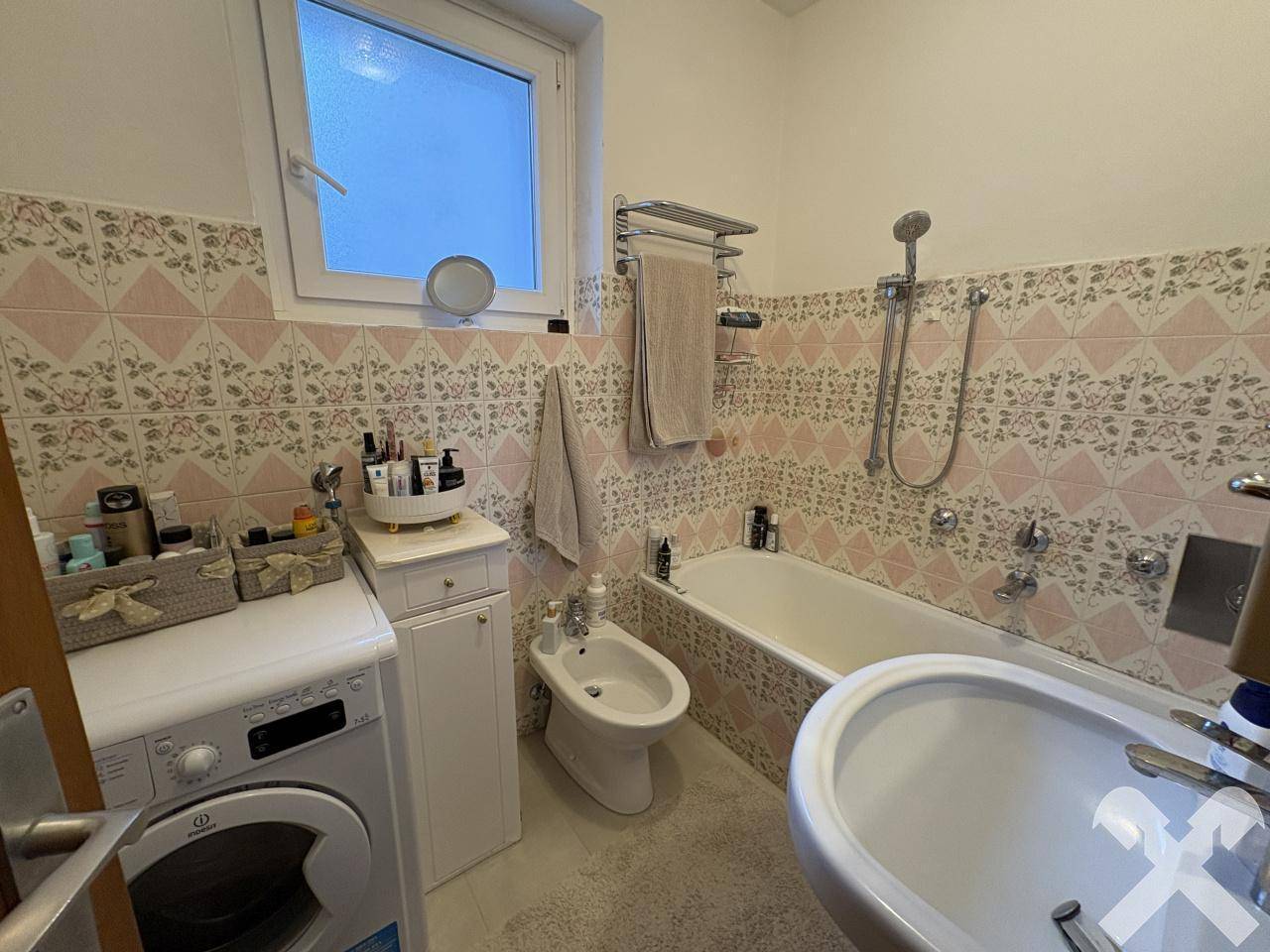 Badezimmer im 80er-Jahre-Stil mit Badewanne, Bidet und Fenster.