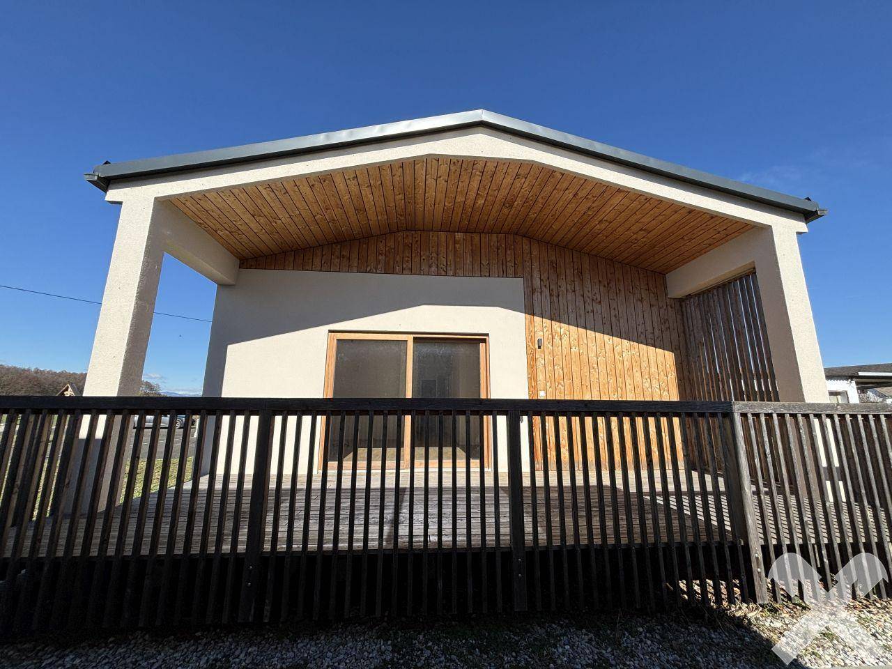Überdachte Terrasse mit Holzverkleidung und modernem Geländer unter klarem Himmel.