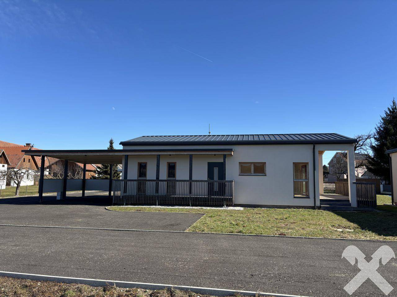 Ansicht des modernen Hauses mit Carport und gepflegter Außenanlage an einem sonnigen Tag.