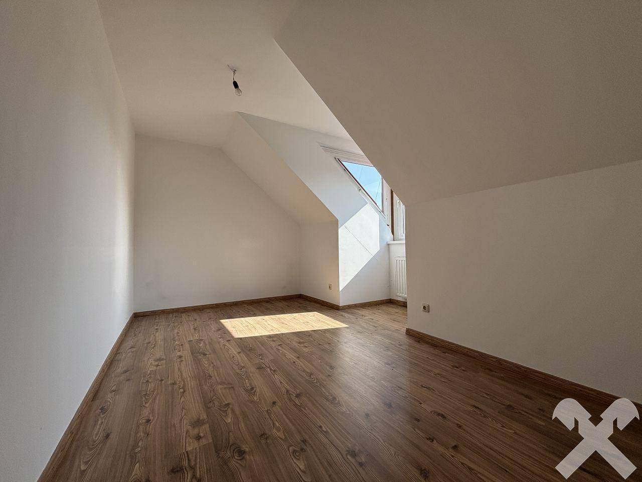Helles Zimmer mit Laminatboden, Dachschräge und großem Fenster.