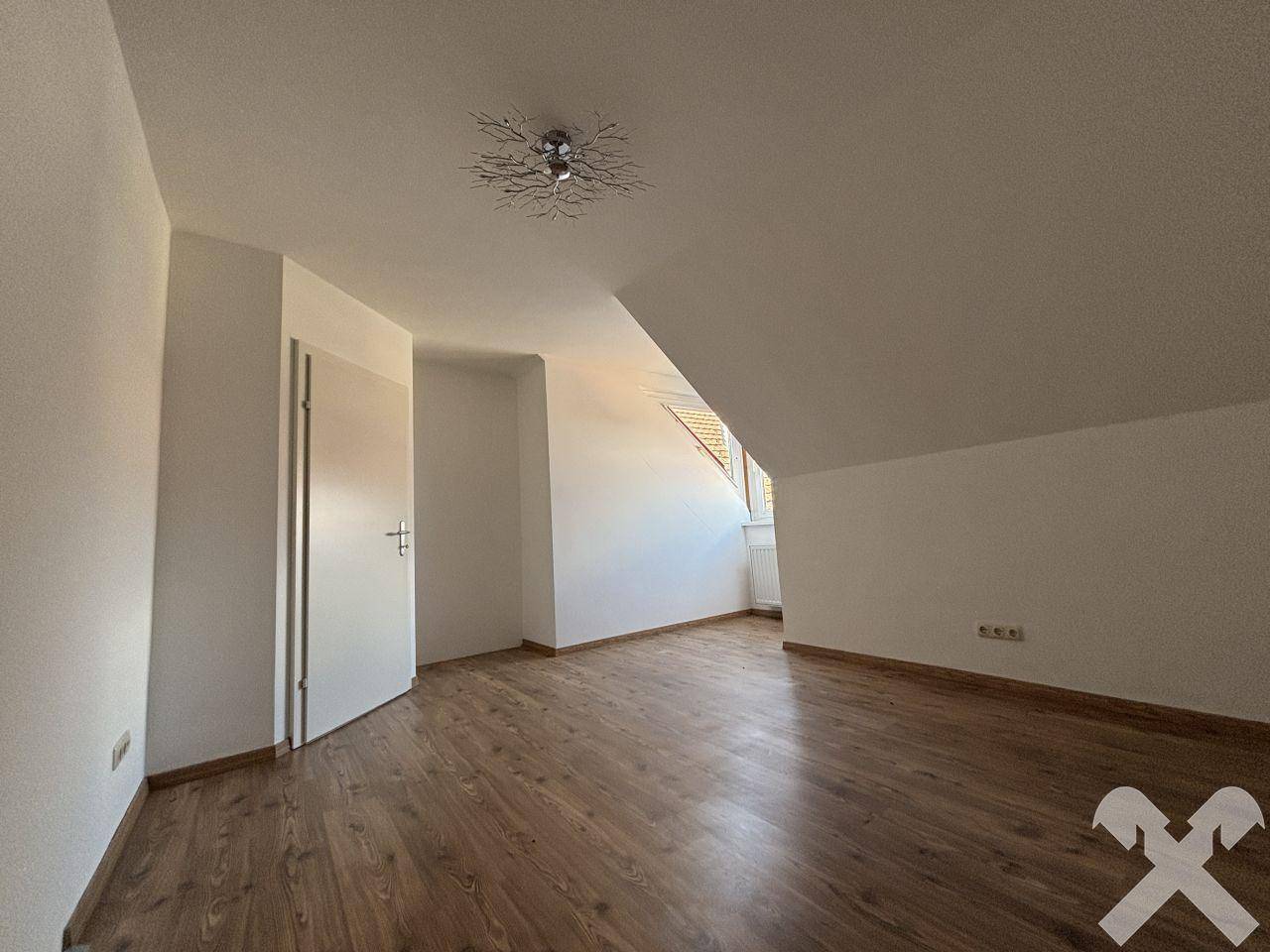 Geräumiges Zimmer mit Laminatboden, Dachschräge und weiß gestrichenen Wänden.