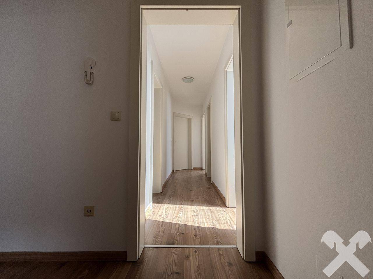 Heller Flur mit Laminatboden, der zu weiteren Zimmern führt und viel Tageslicht bietet.