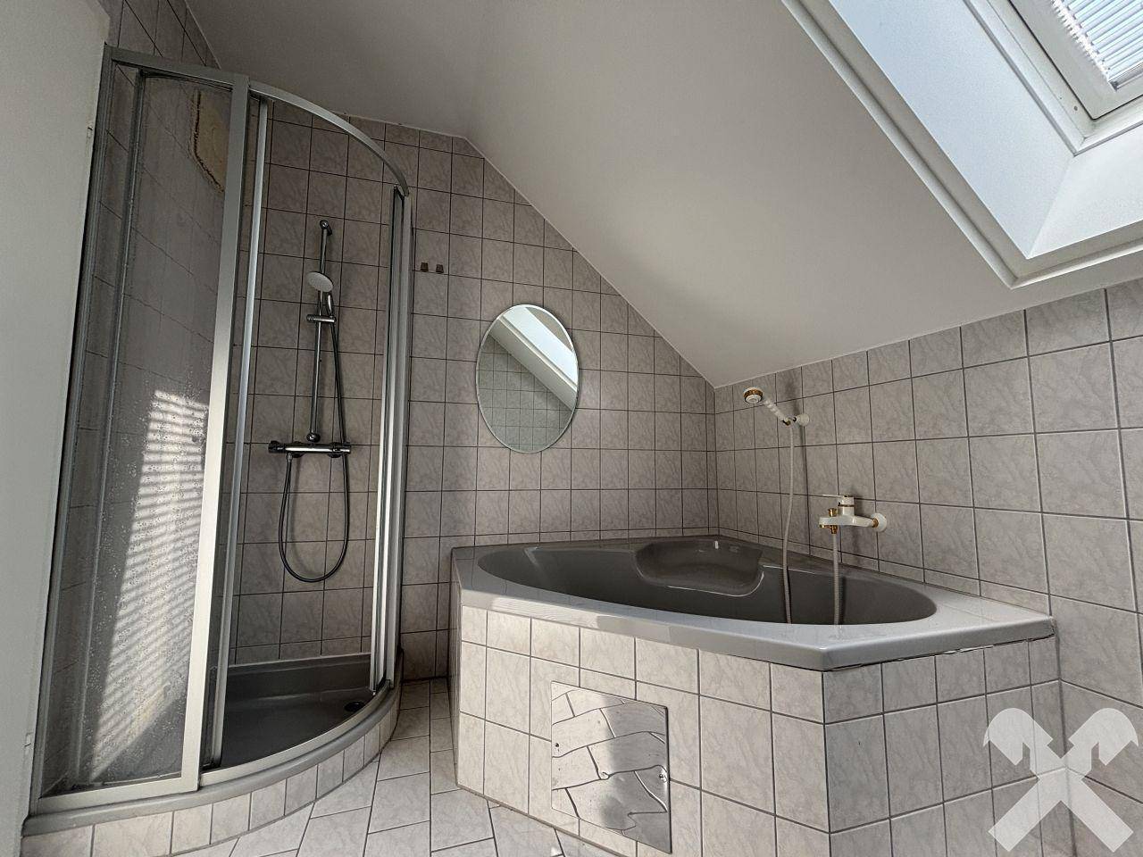 Badezimmer mit Eckbadewanne, Duschkabine und Dachschräge.