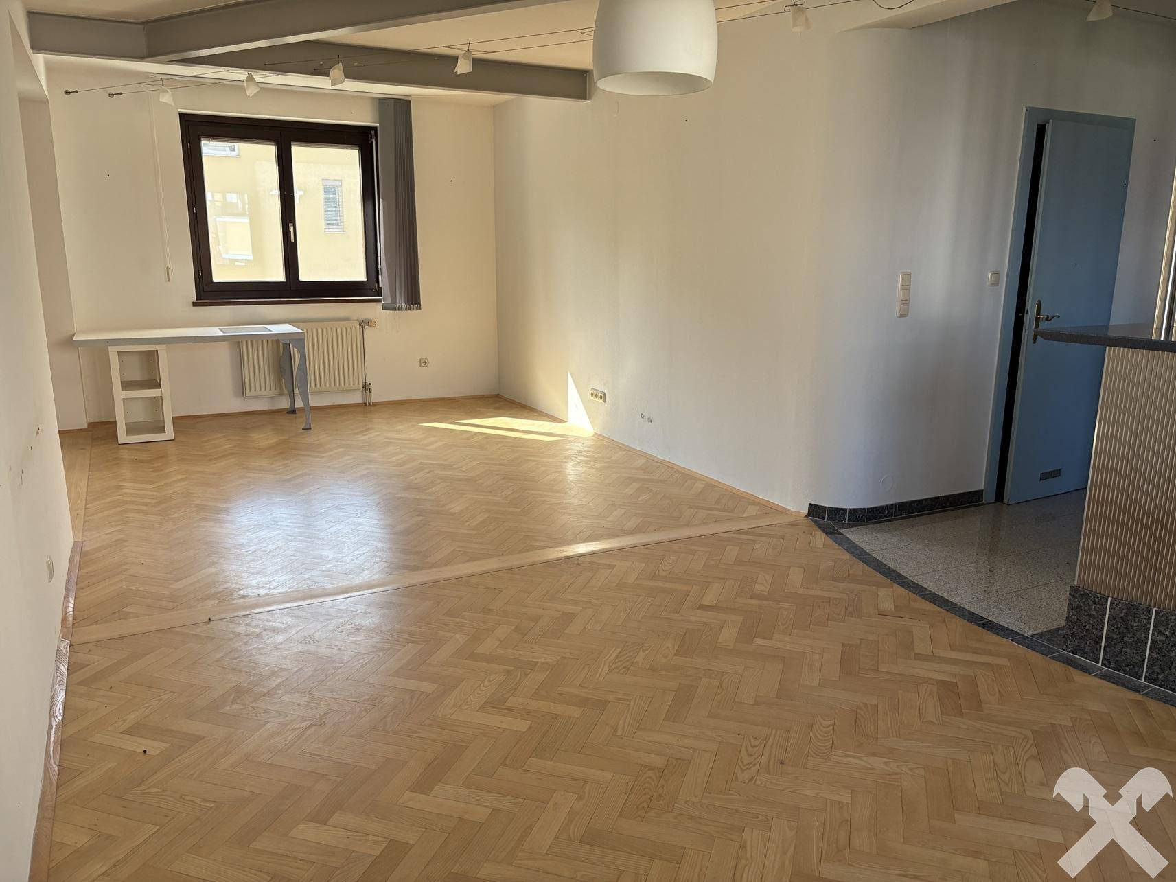 Offener Wohnbereich mit Parkettboden und Übergang zu gefliestem Eingangsbereich, bietet viel Platz.