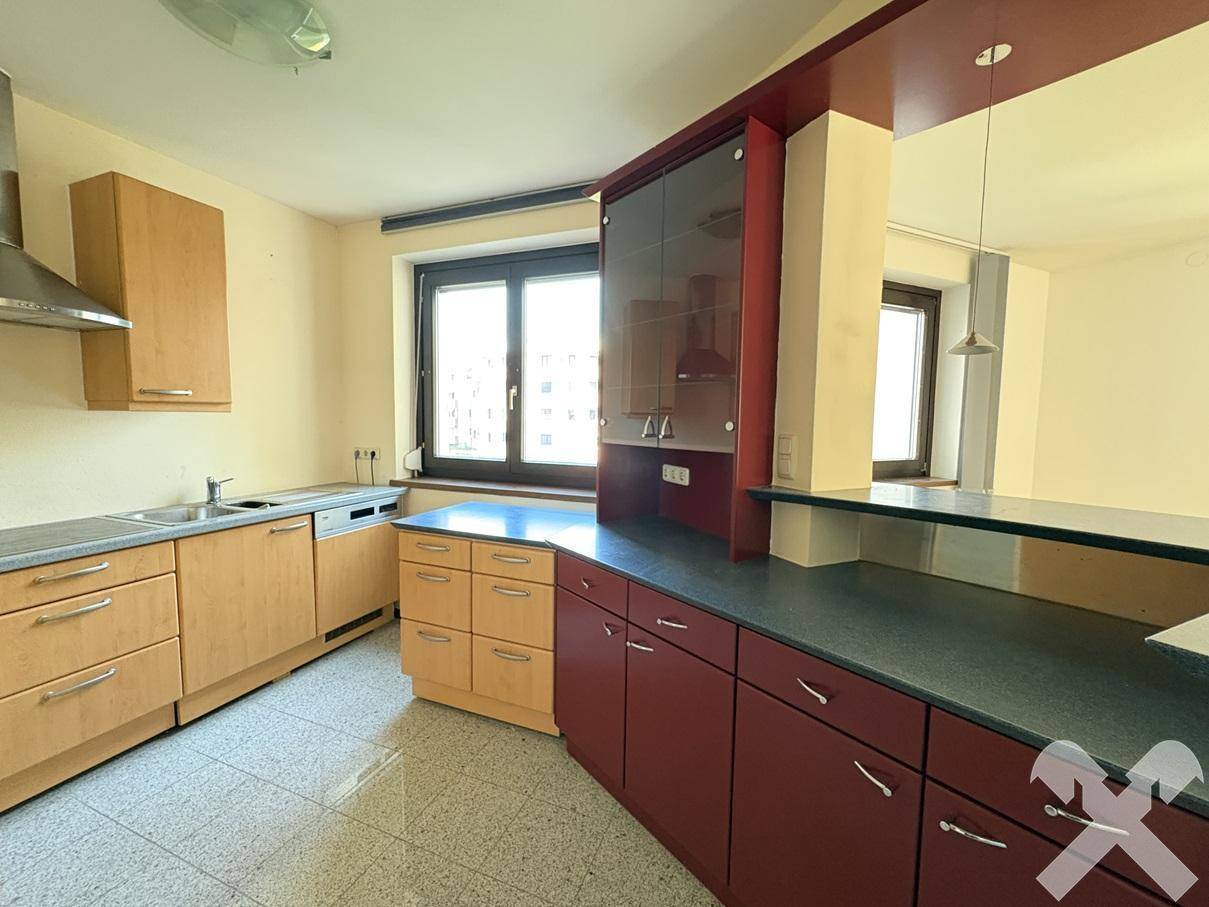 Funktionale Küche mit Holzschränken, Arbeitsplatte und Fenster, bietet ausreichend Stauraum.