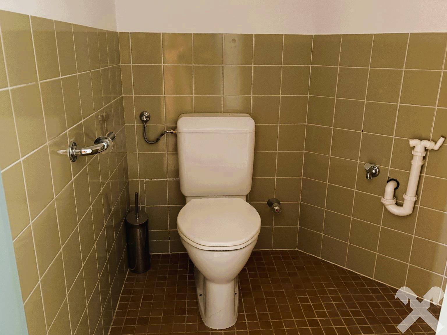 Separates WC mit beigefarbenen Fliesen und Standard-Toilette, sauber und funktional.