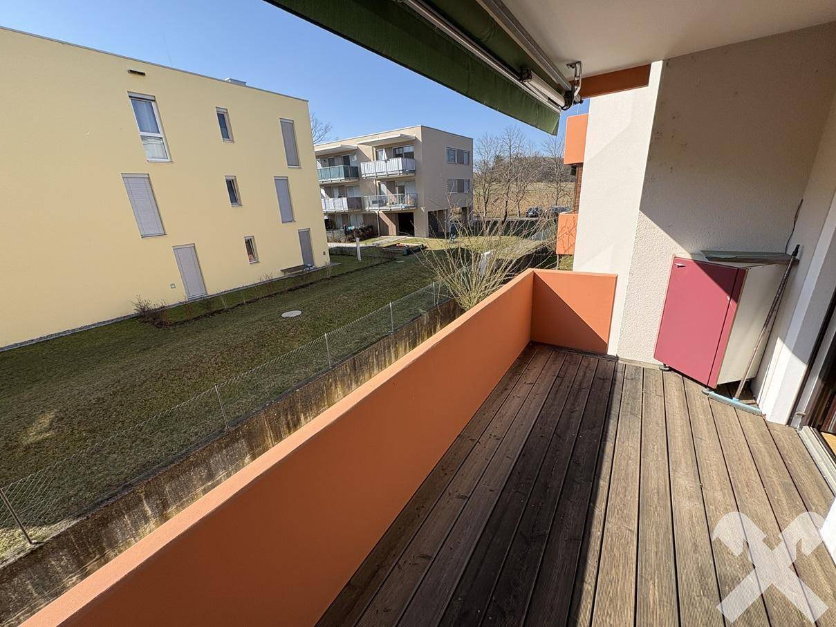 Geräumiger Balkon mit Holzboden und Blick auf die grüne Umgebung, bietet viel frische Luft.