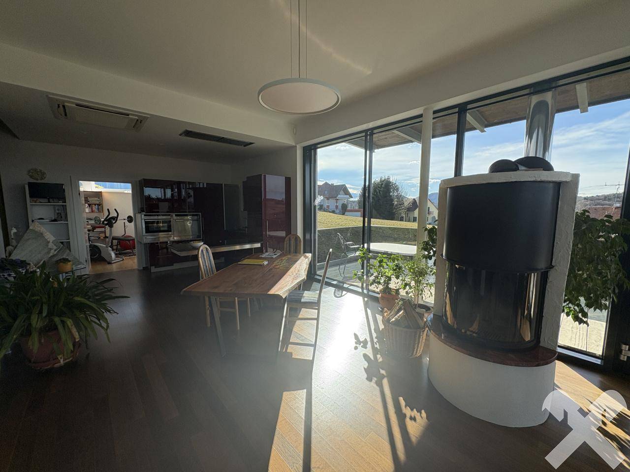 Heller Wohn-Essbereich mit Kaminofen, großen Glasfronten und Zugang zur Terrasse.