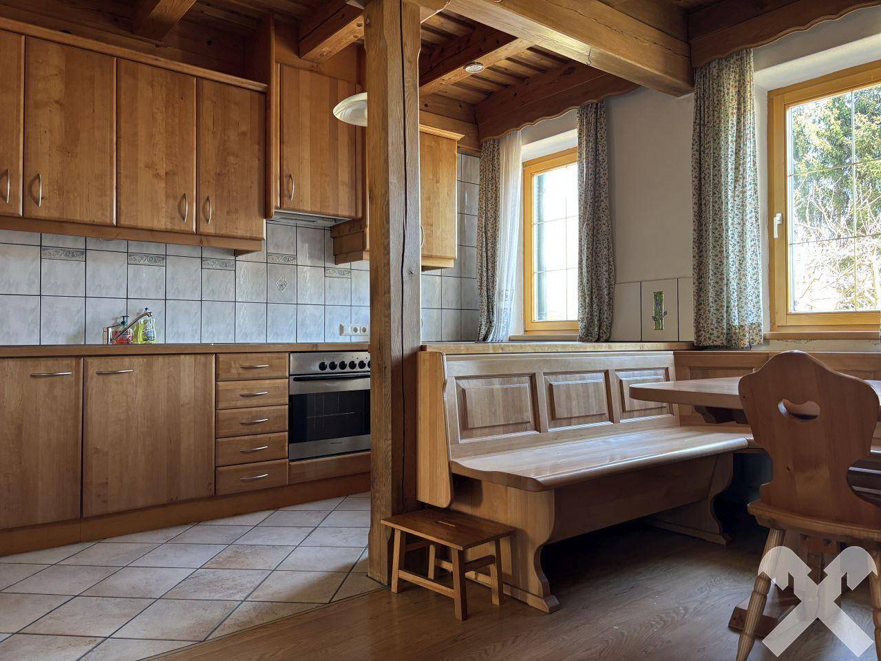Gemütliche Wohnküche im Landhausstil mit Holzeinbauten, Essbereich und Fliesenboden.