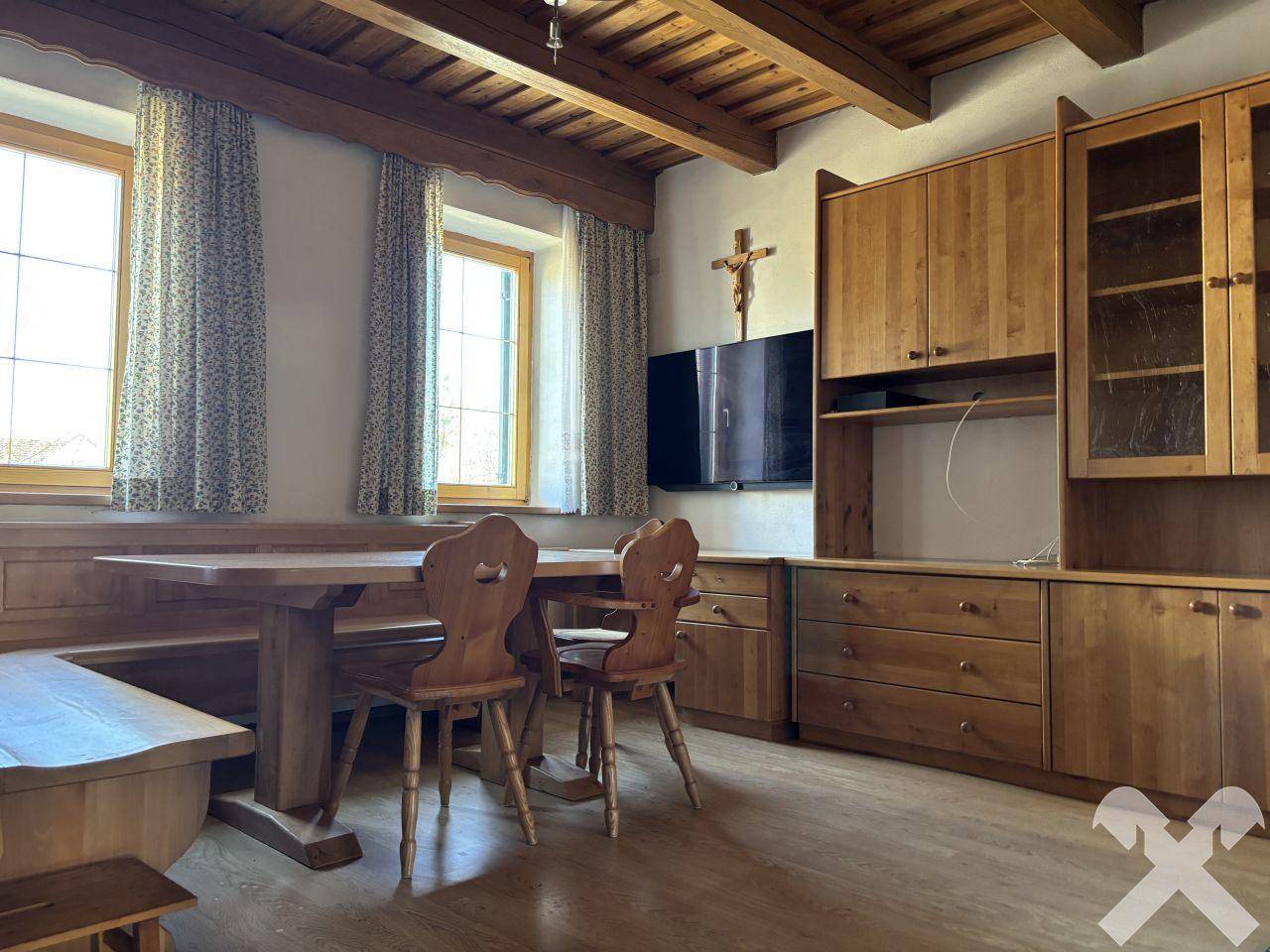 Rustikaler Essbereich mit Holztisch, Eckbank und passenden Holzmöbeln unter Holzbalkendecke.