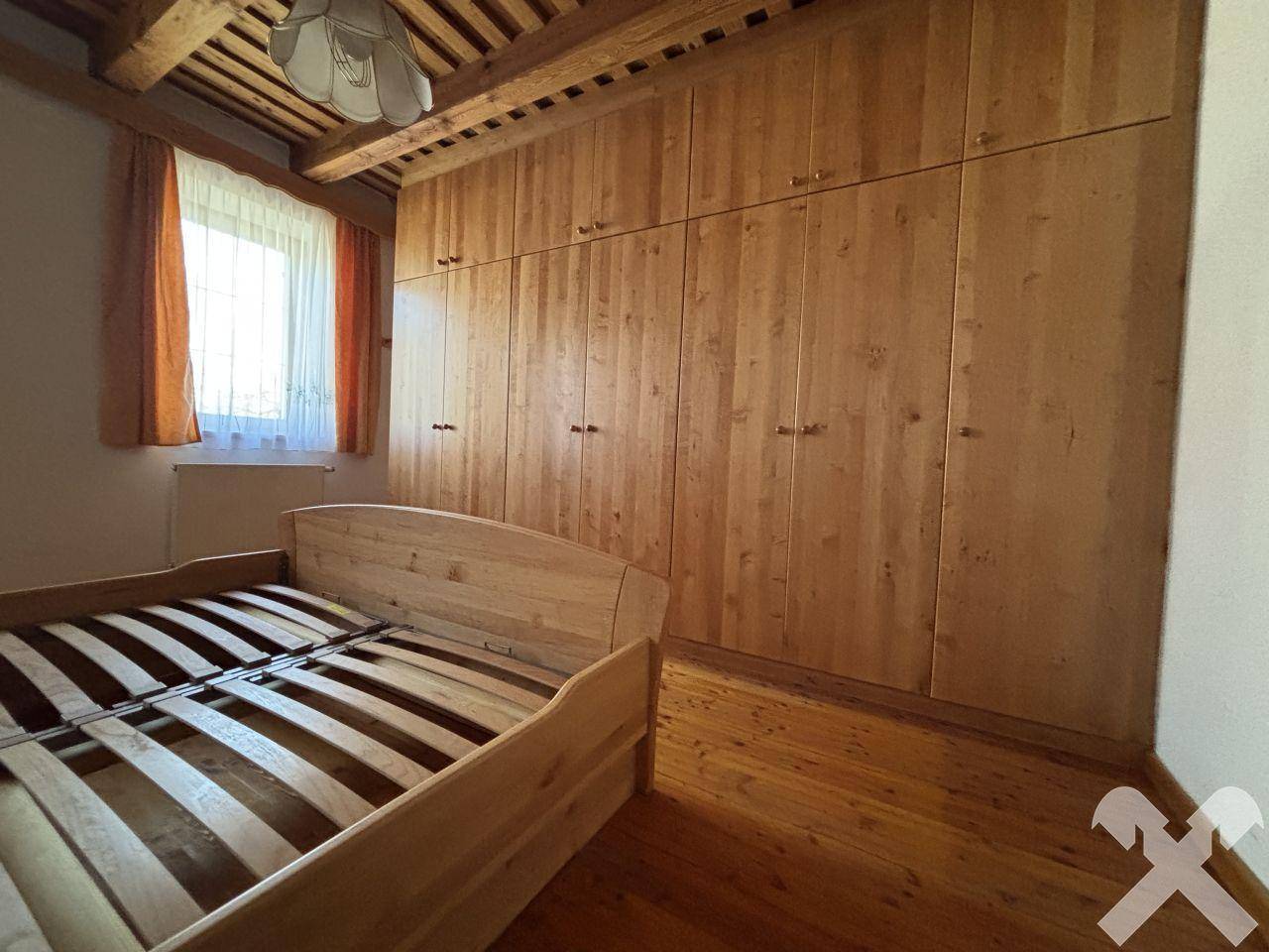 Schlafzimmer mit großen Einbauschränken aus Holz und Holzbalkendecke.