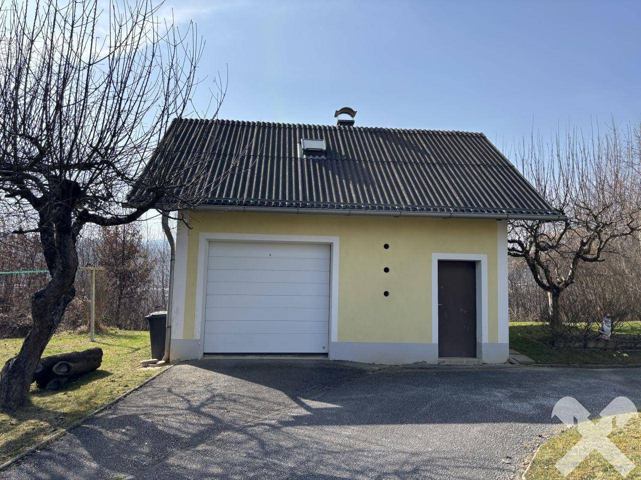 Separate Garage mit Schwingtor und Satteldach neben dem Haupthaus auf dem Grundstück.