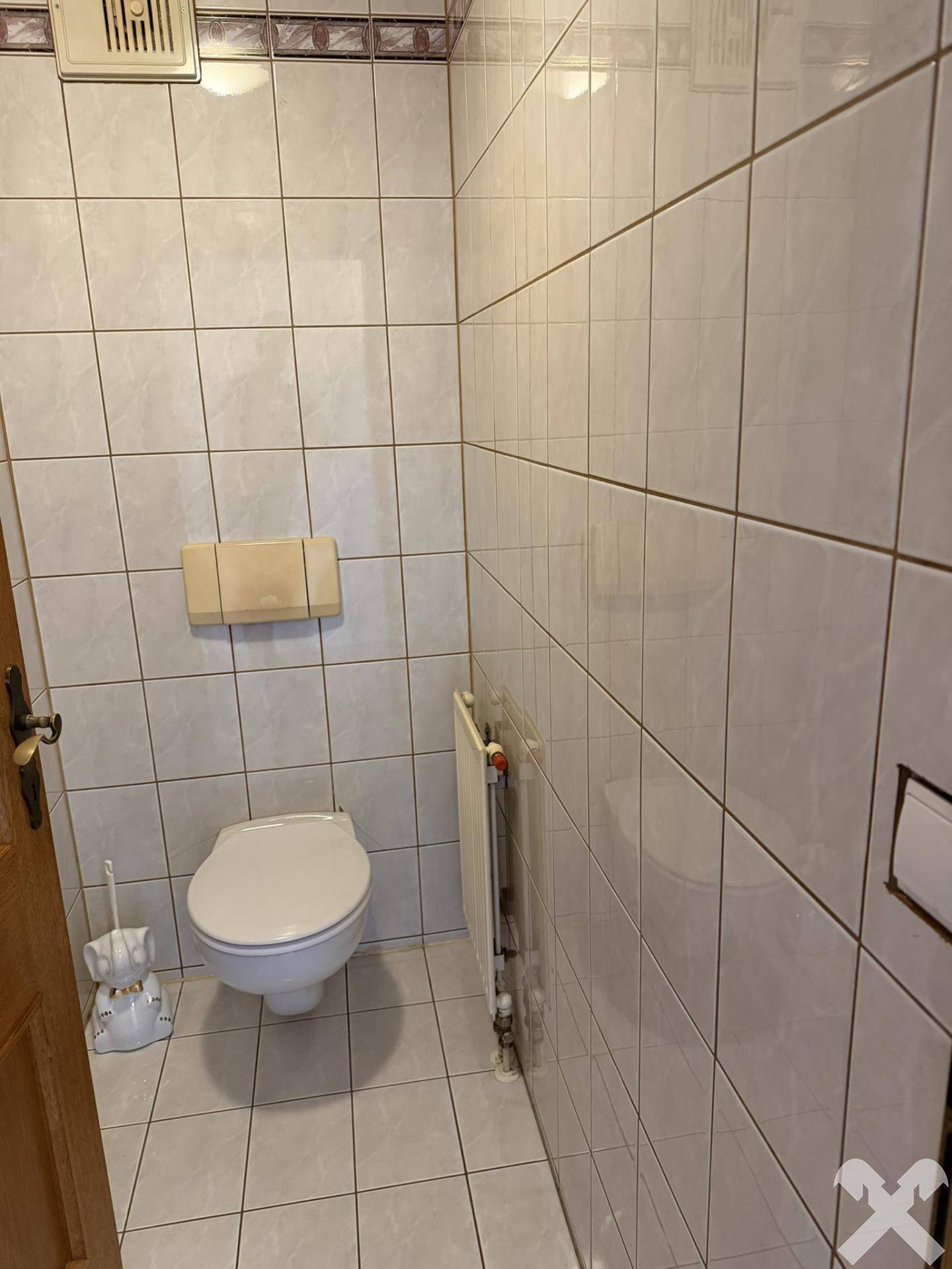 Kleines Gäste-WC mit weißen Fliesen und Heizkörper, funktional und sauber.