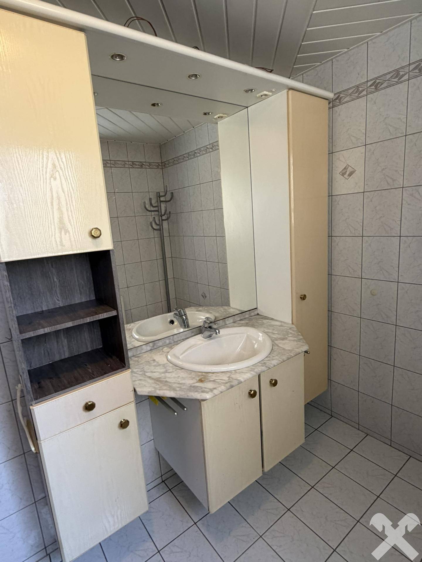 Badezimmer mit Einzelwaschbecken, Spiegelschrank und hellen Fliesen, gut gepflegt.