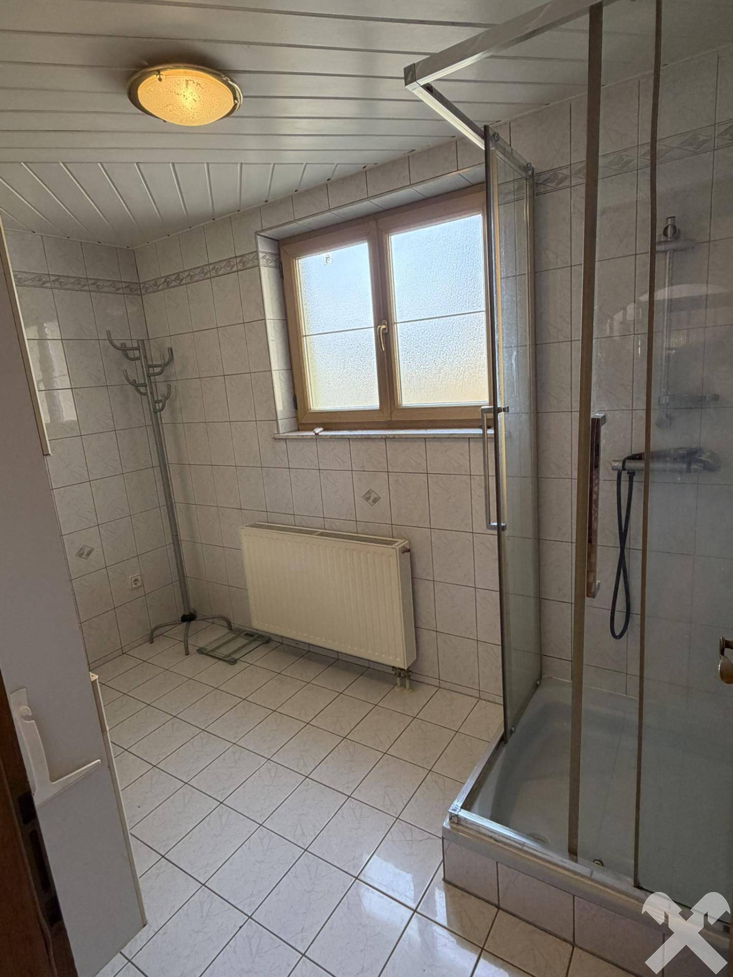 Badezimmer mit Duschkabine, Fenster und weißen Fliesen, hell und praktisch.