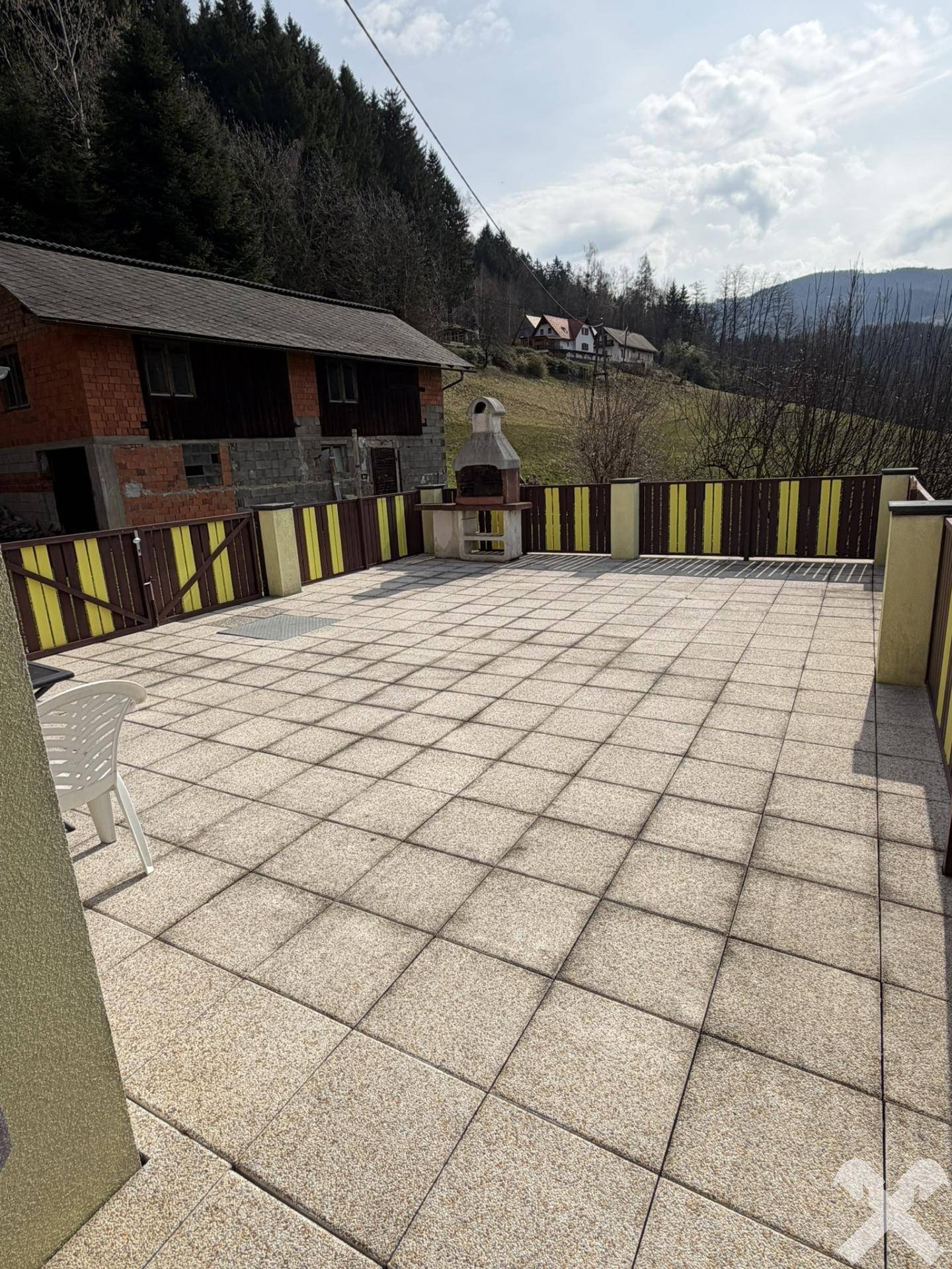 Große gepflasterte Terrasse mit fest installiertem Grill, perfekt für gesellige Abende.