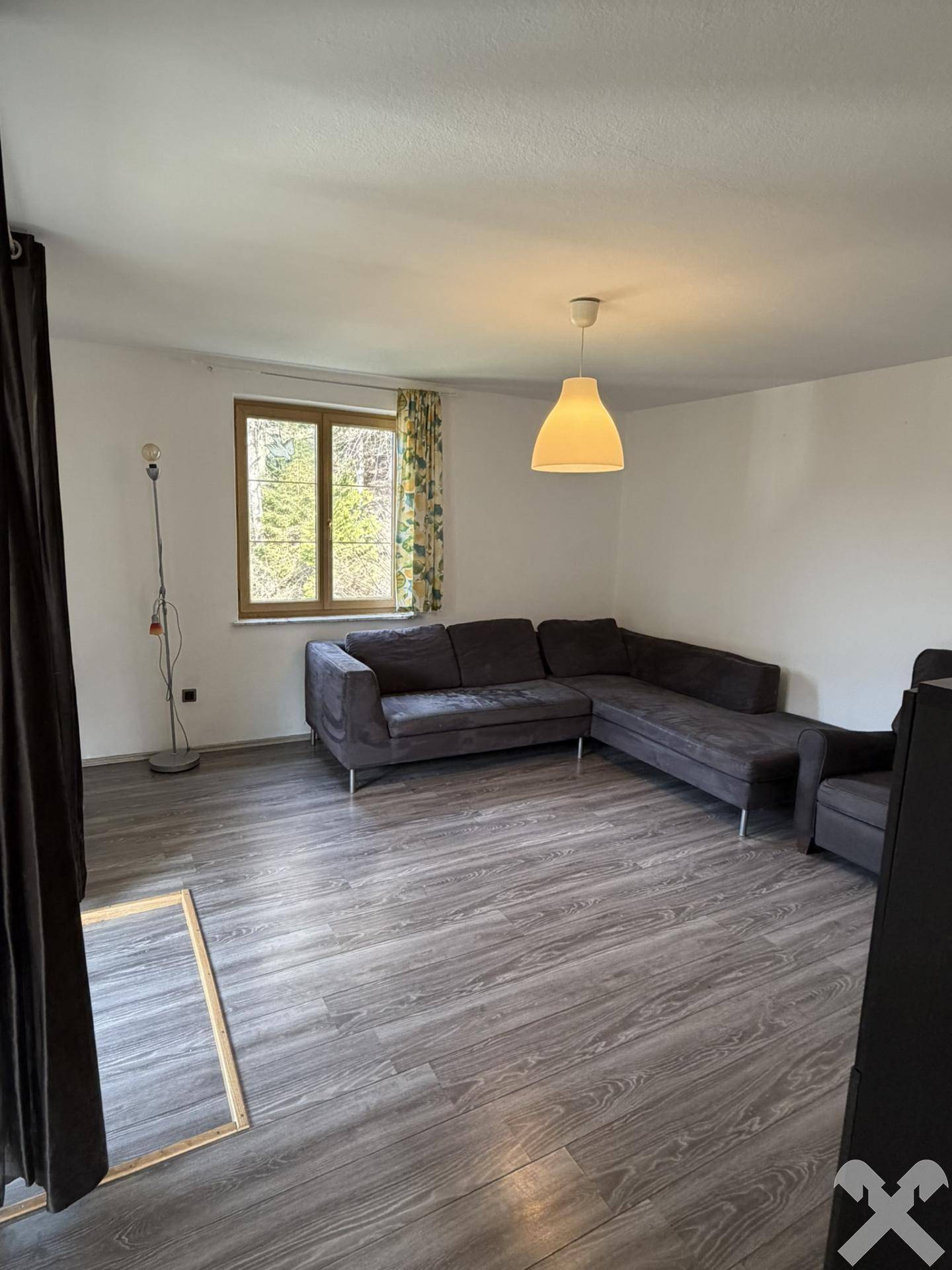 Gemütliches Wohnzimmer mit großem Ecksofa und Laminatboden, ideal zum Entspannen.