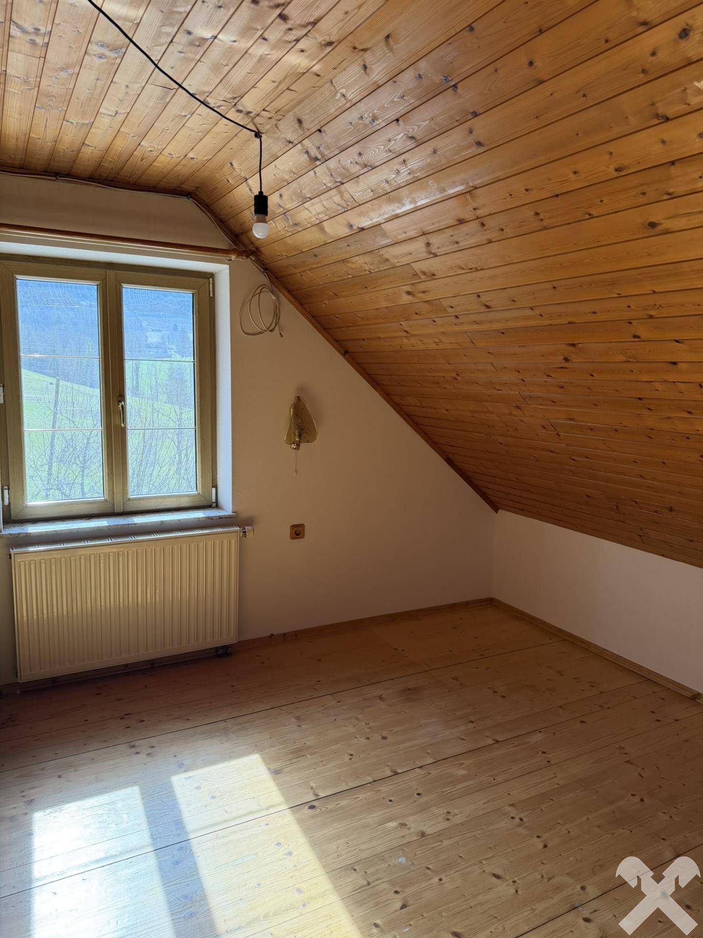 Helles Schlafzimmer im Dachgeschoss mit Holzboden und schräger Decke, bietet viel Tageslicht.