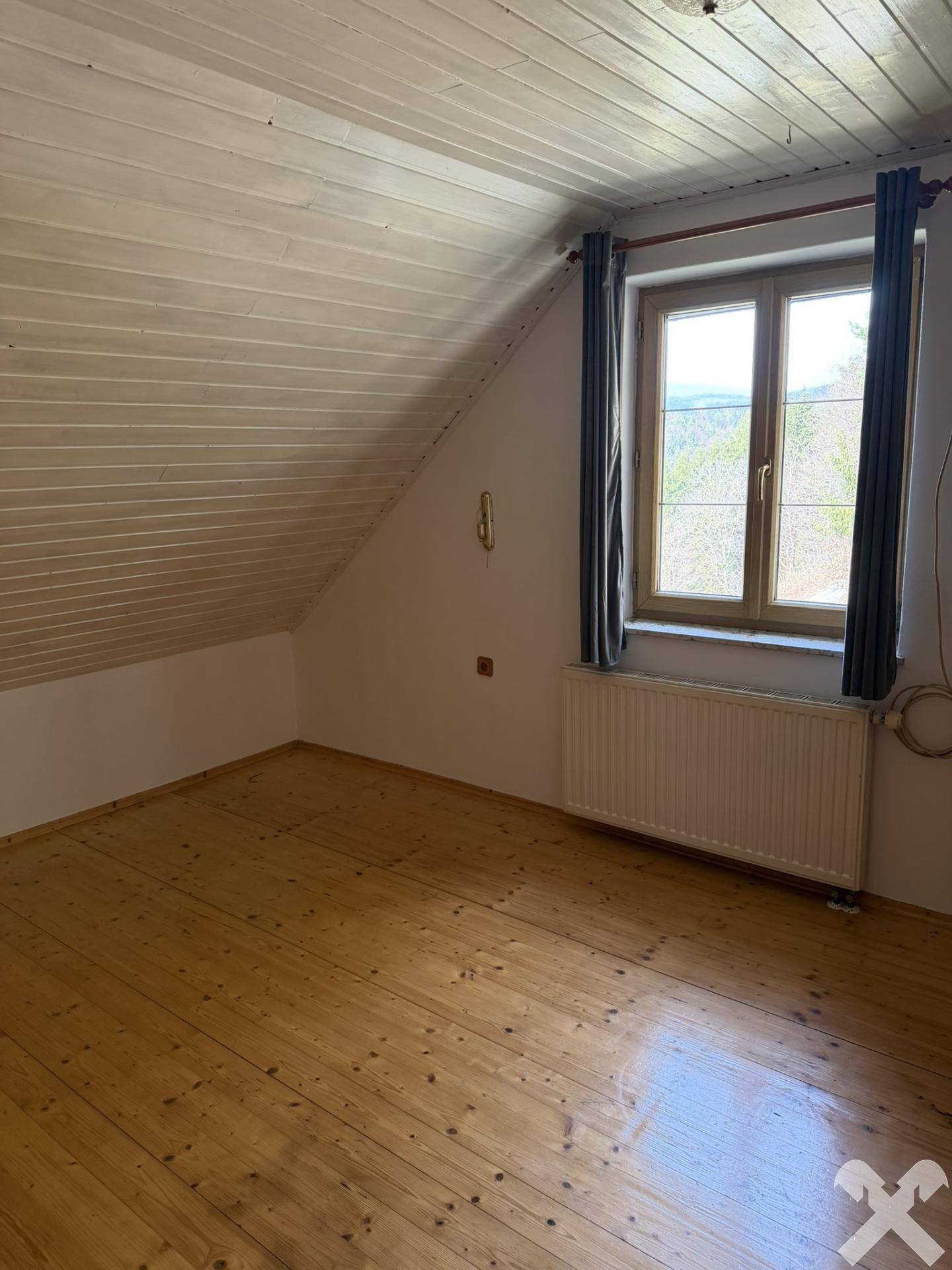 Dachgeschosszimmer mit Holzboden und schräger Decke, ideal als Kinder- oder Gästezimmer.
