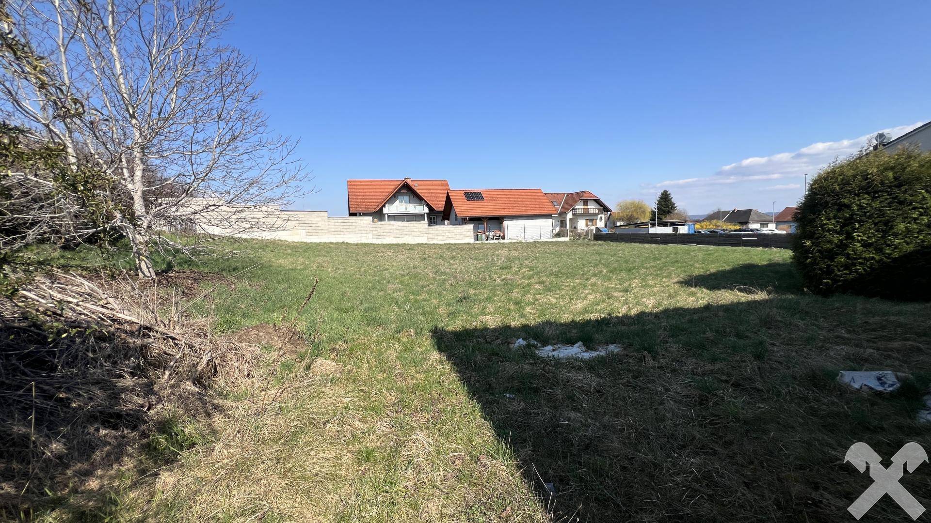 Weitläufige Grasfläche mit Blick auf eine Reihe von Wohnhäusern und einen blauen Himmel.