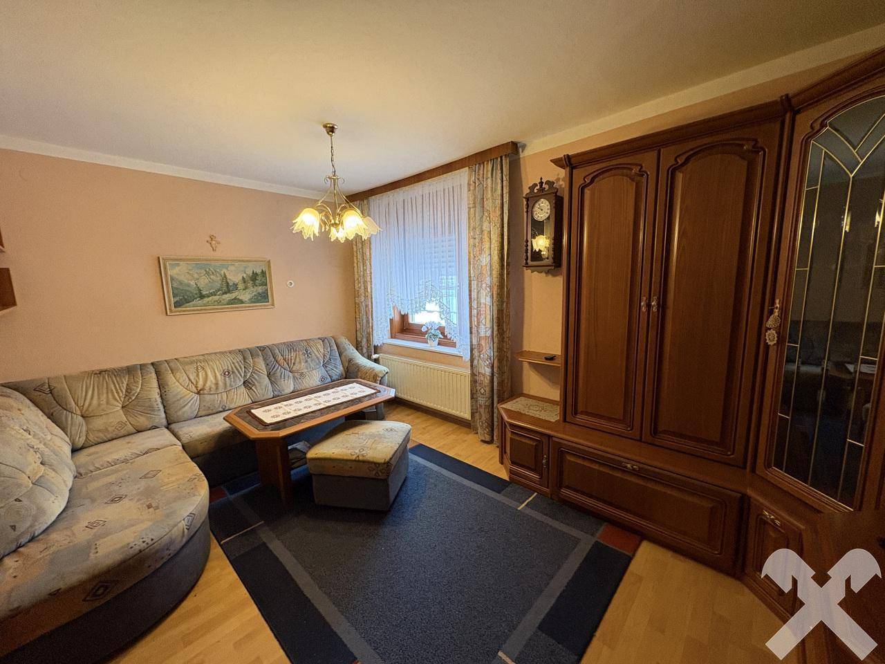 Gemütliches Wohnzimmer mit traditionellen Holzmöbeln, Sofa und Teppichboden.