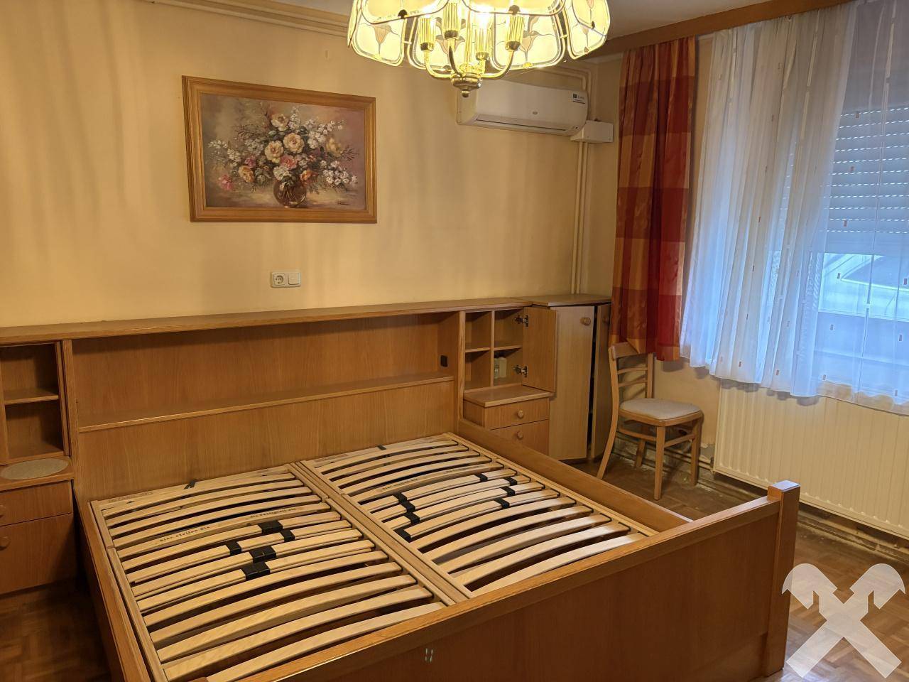 Schlafzimmer mit Doppelbett, Holzrahmen und Klimaanlage an der Wand.