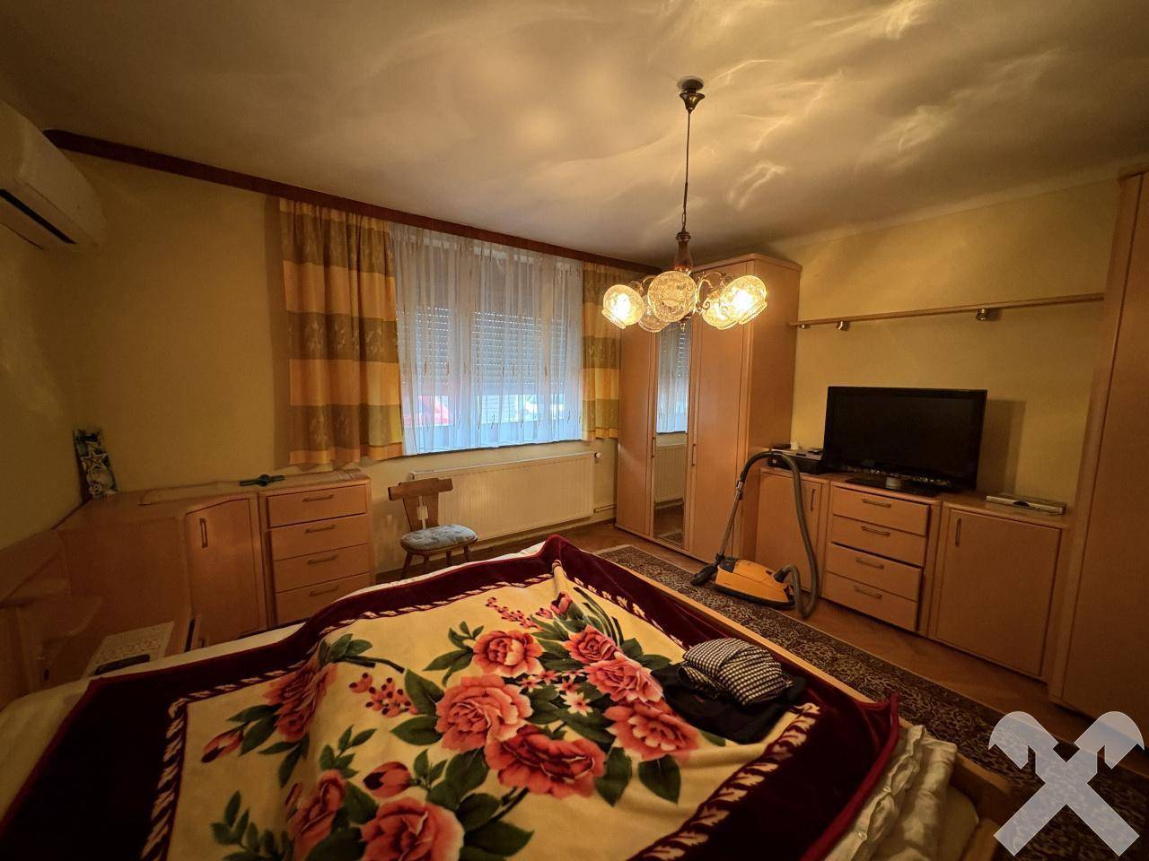 Schlafzimmer mit Holzbett, Schränken und einem Fenster mit Vorhängen.