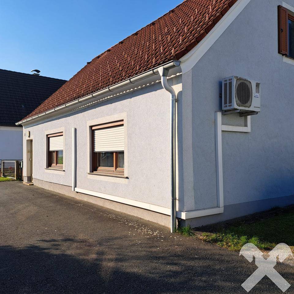 Seitenansicht des Hauses mit Klimaanlage an der Fassade und Rollläden an den Fenstern.