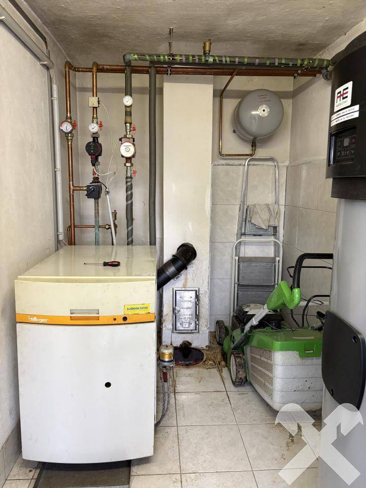 Heizungsraum mit Kessel, Rohren und einem Warmwasserspeicher.