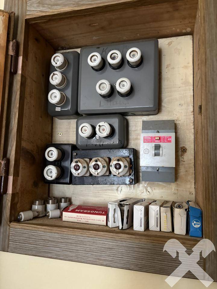 Alter Sicherungskasten mit Keramiksicherungen in einem Holzschrank.