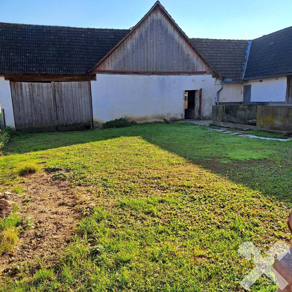 Großer Gartenbereich mit Rasenfläche und einem alten Nebengebäude im Hintergrund.