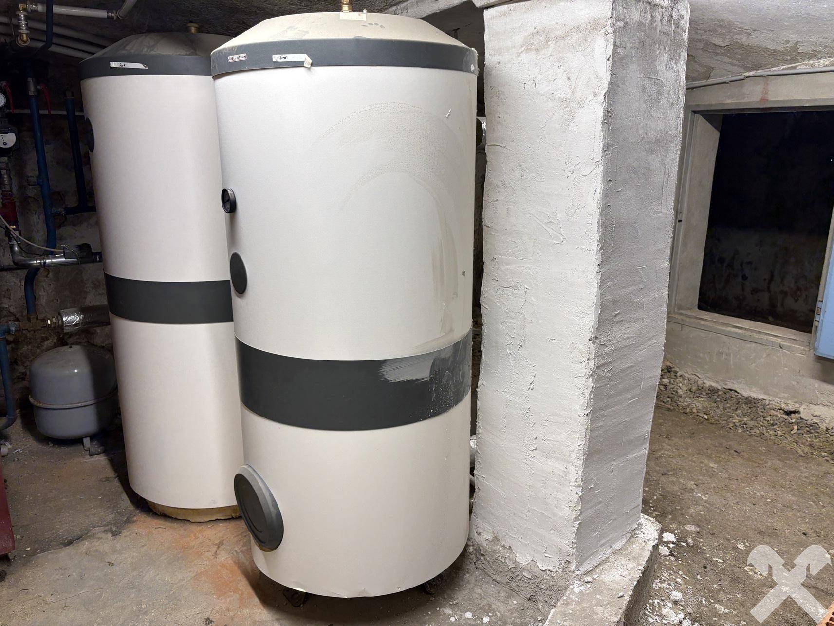 Technikraum im Keller mit zwei großen Warmwasserspeichern und sichtbaren Installationen.