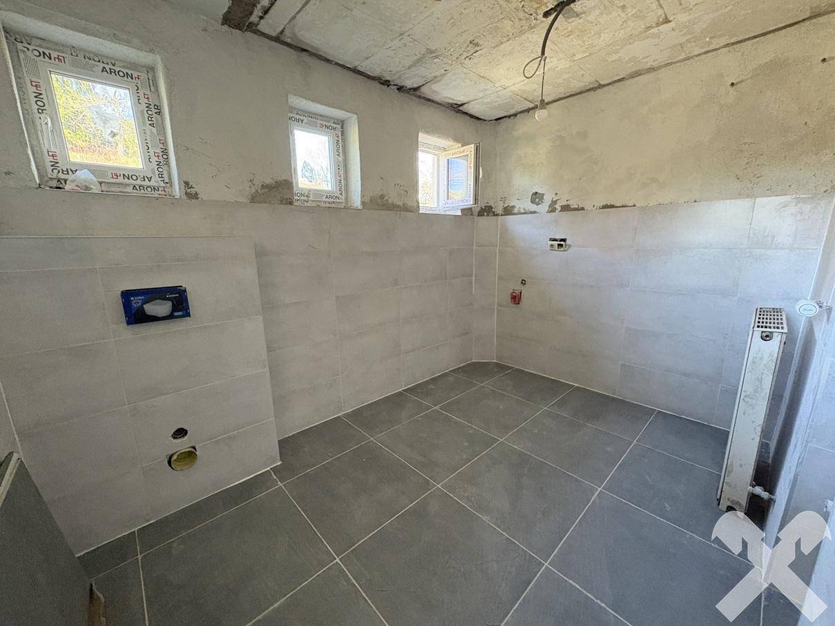 Badezimmer in Renovierung mit neuen Fliesen an Wänden und Boden, bereit für die Installation.