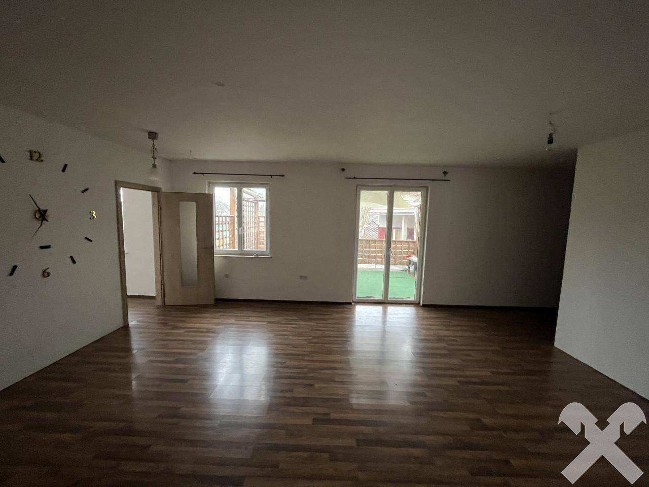 Heller Wohnraum mit Holzboden und Zugang zu einem Außenbereich durch eine Terrassentür.