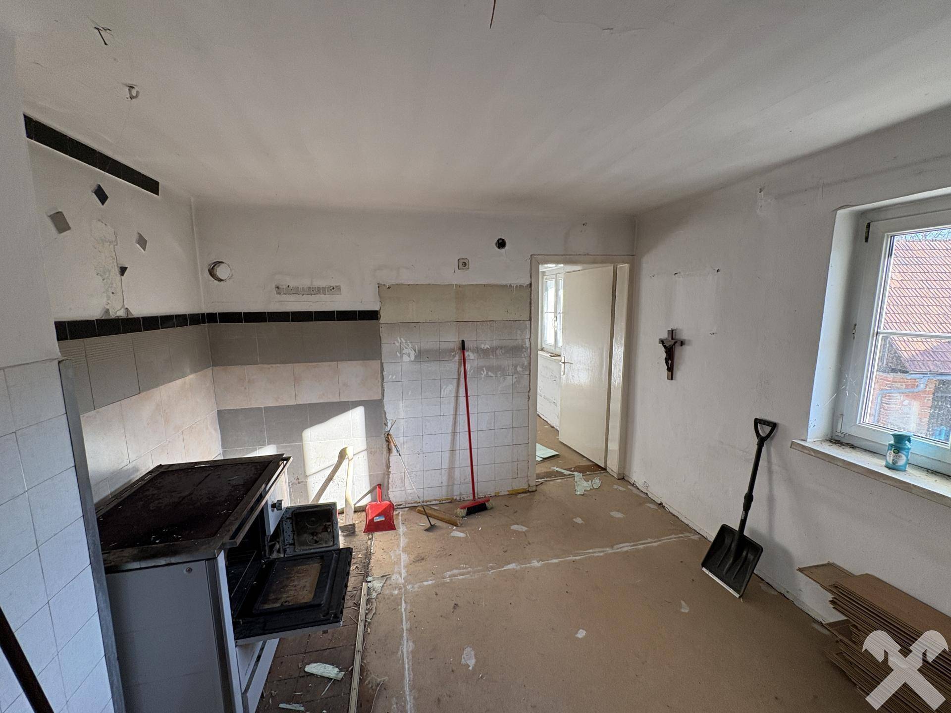 Alte Küche in Renovierung mit Fliesen und einem traditionellen Holzofen.
