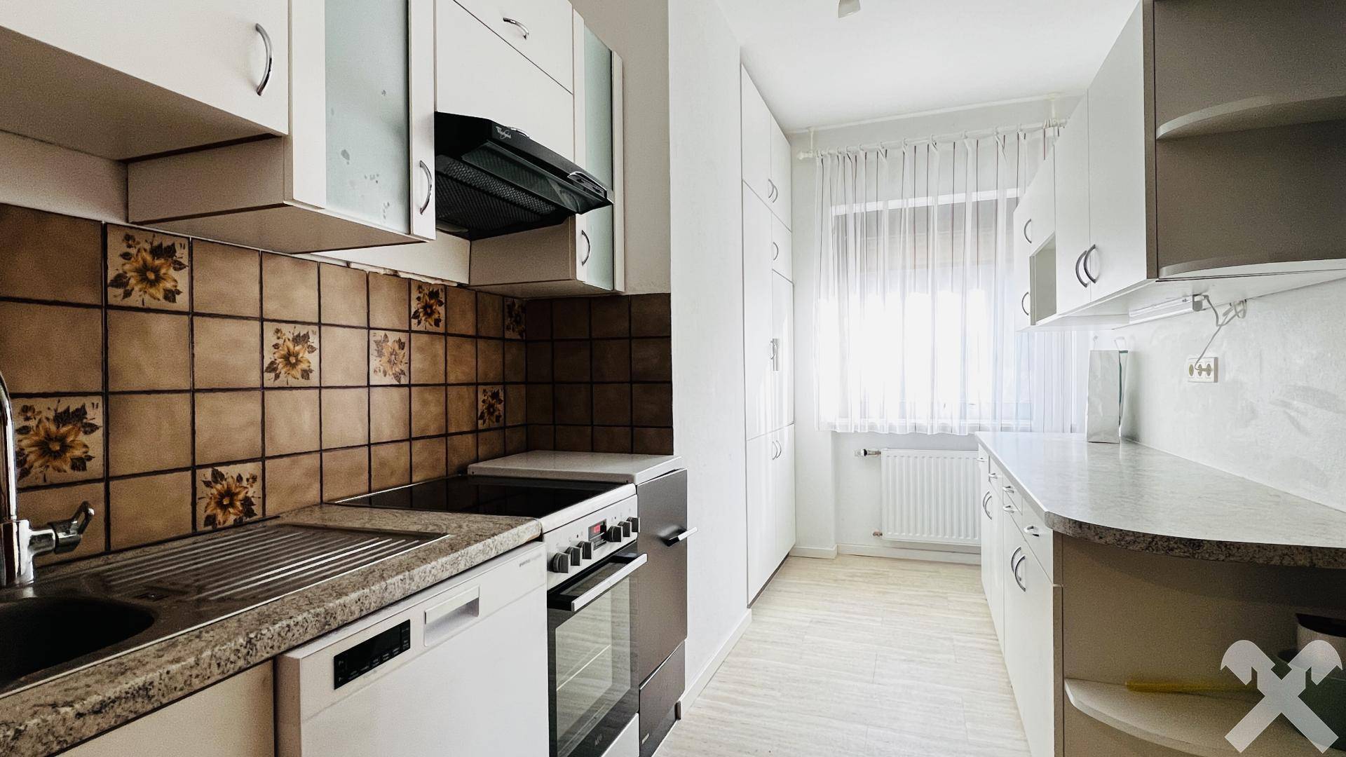Funktionale Küche mit weißen Schränken, Fliesenrückwand und Fenster.