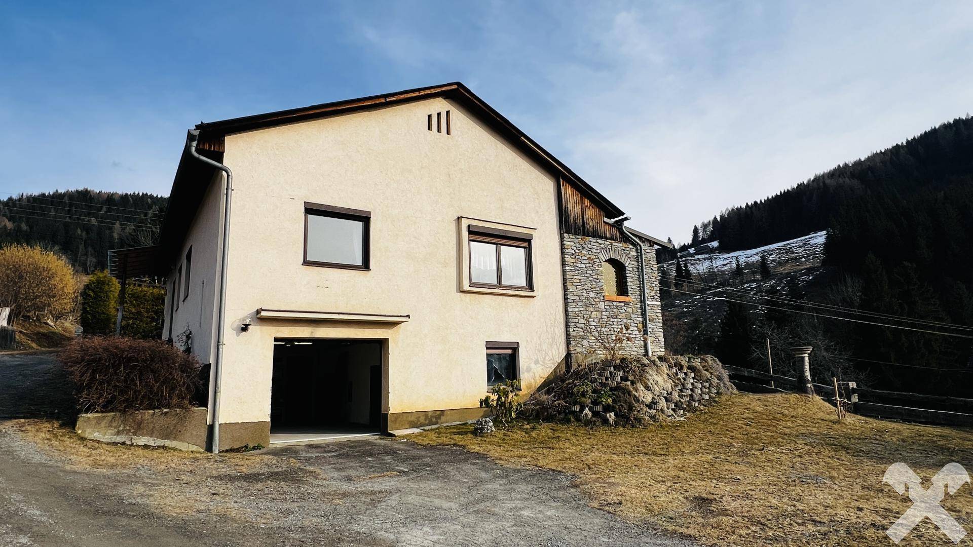 Rückansicht des Hauses mit integrierter Garage und ländlicher Umgebung.