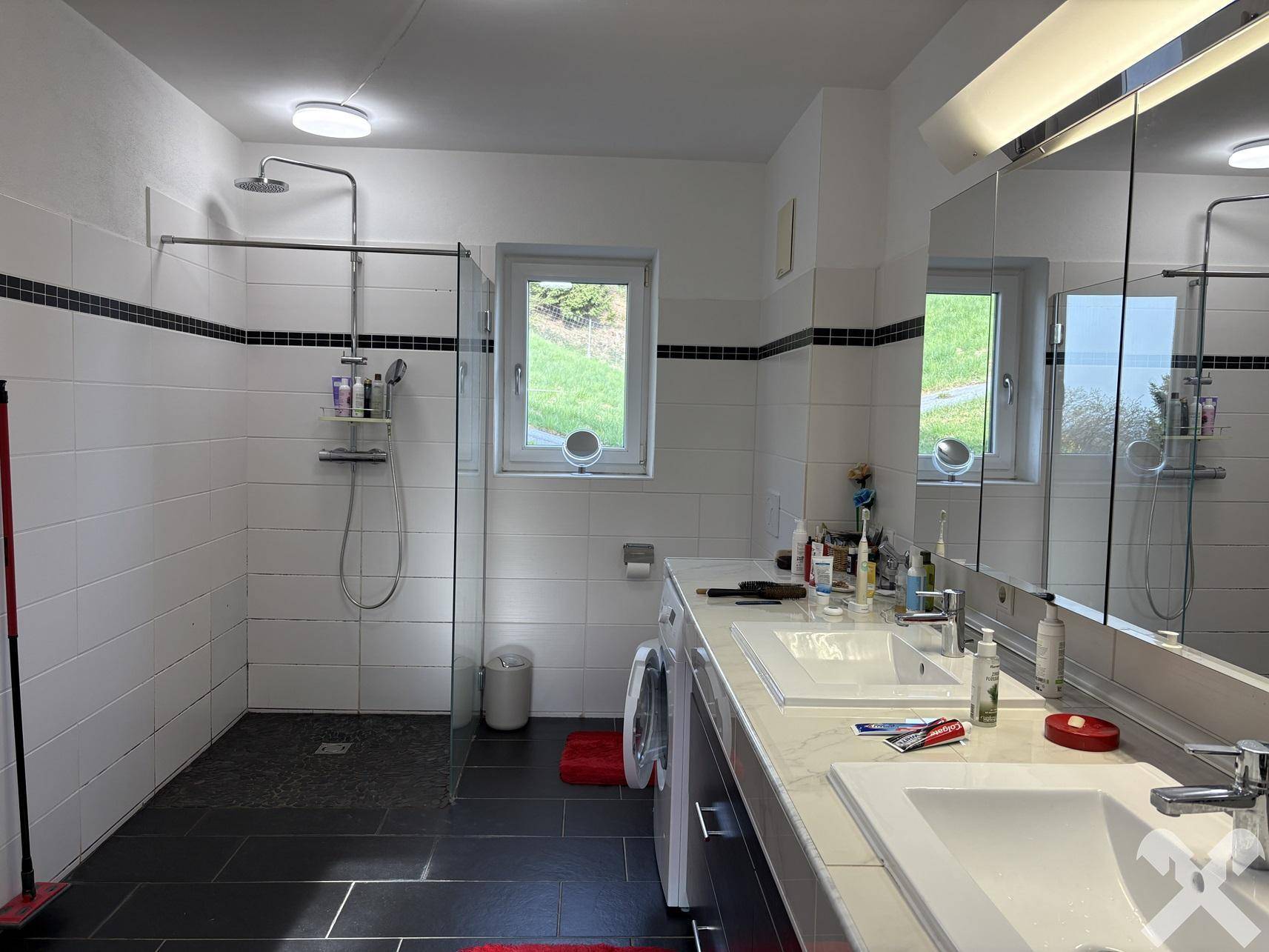 Modernes Badezimmer mit begehbarer Dusche, Doppelwaschbecken und Fenster, in Schwarz-Weiß-Design.