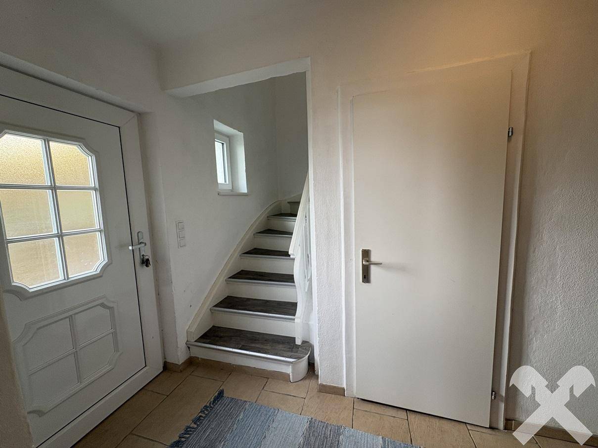 Eingangsbereich mit Fliesenboden und Treppe zum Obergeschoss, hell und funktional.