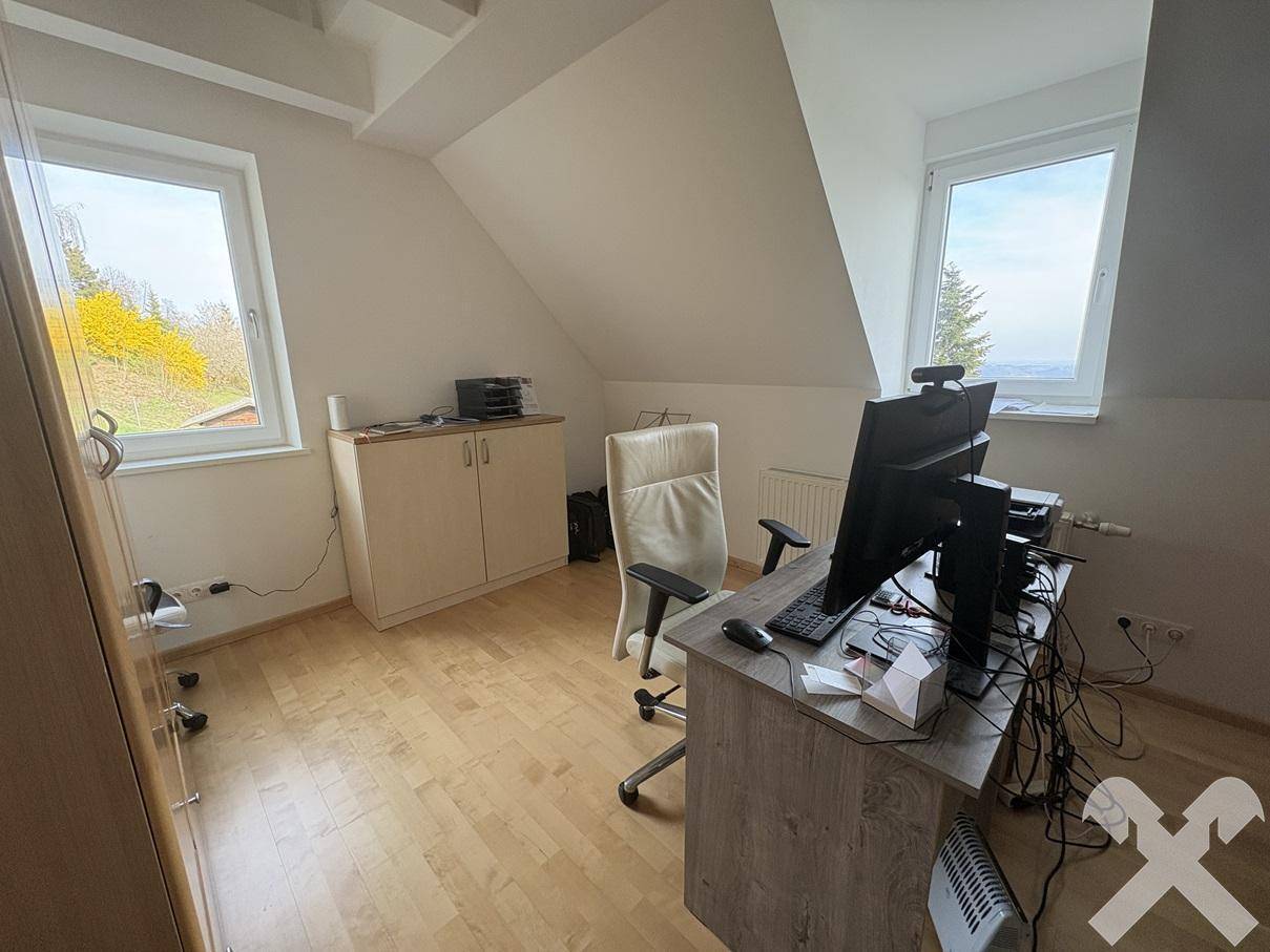 Helles Arbeitszimmer mit Holzboden und zwei Fenstern, ideal für konzentriertes Arbeiten.
