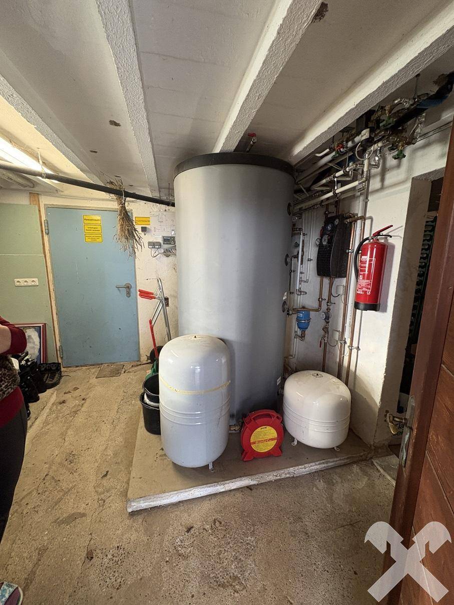 Technikraum im Keller mit Warmwasserspeicher und Heizungsinstallationen.